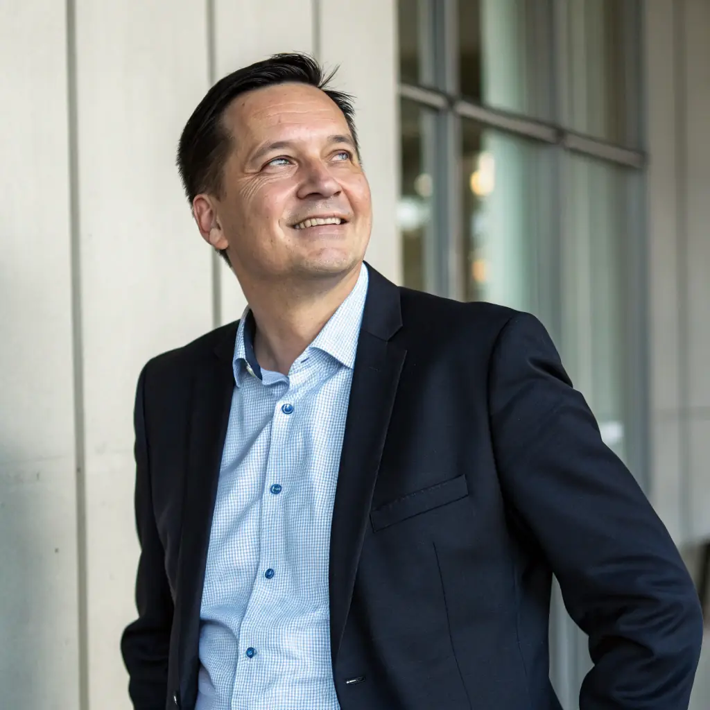 A professional portrait of a middle-aged French man with short hair, wearing a suit and tie, smiling confidently. He is the President of the COMBAT JU-JUTSU CONFEDERATION FRANCE (CJJCF).